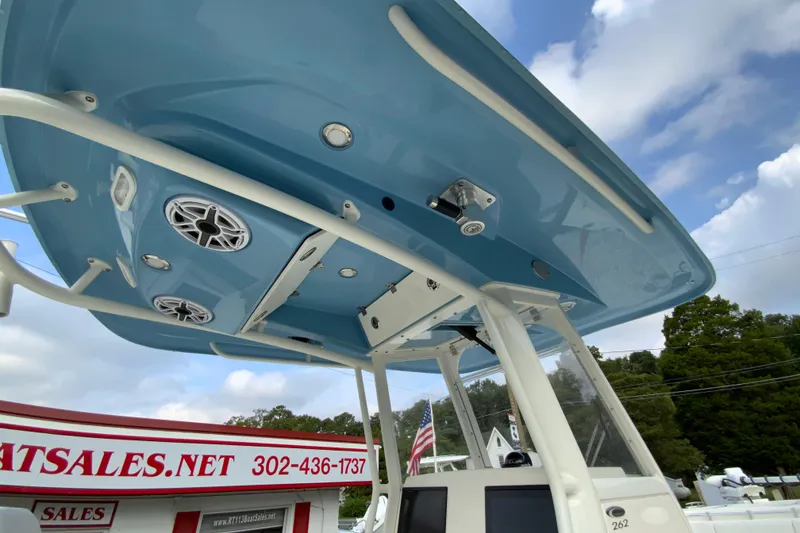Slide: The Image of 2023 Cobia 262 Center Console boat with blue T-top and speakers, dealership background. - 45