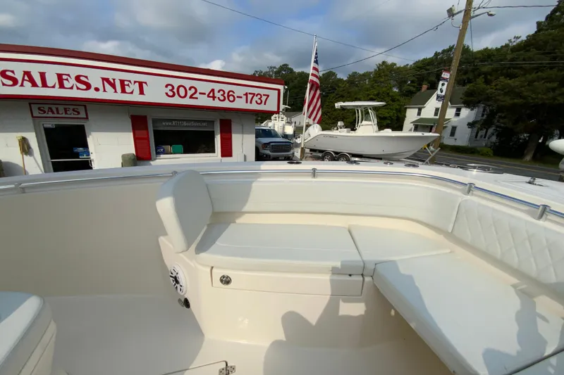 Slide: The Image of 2023 Cobia 262 Center Console boat at dealership with American flag and sales building. - 57