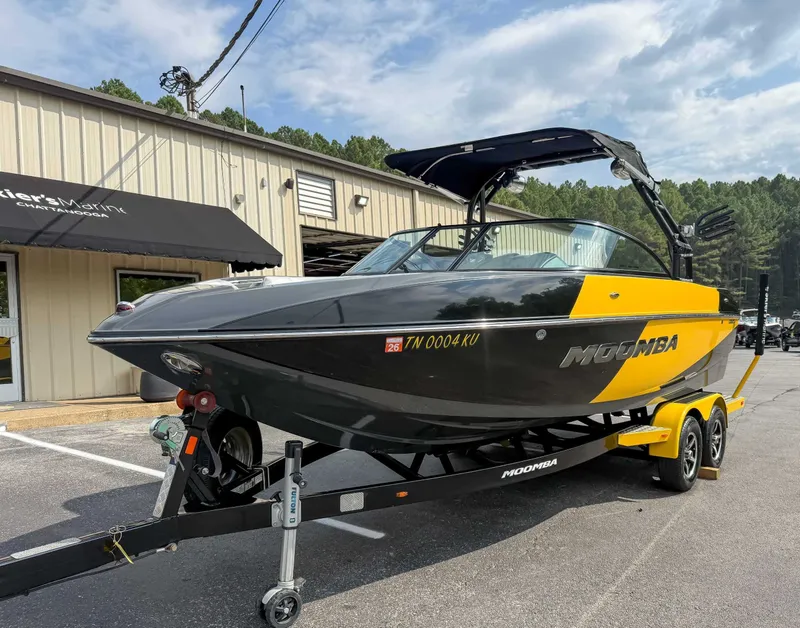 Slide: The Image of 2016 Moomba Craz boat on trailer, black and yellow, parked outside a building. - 3
