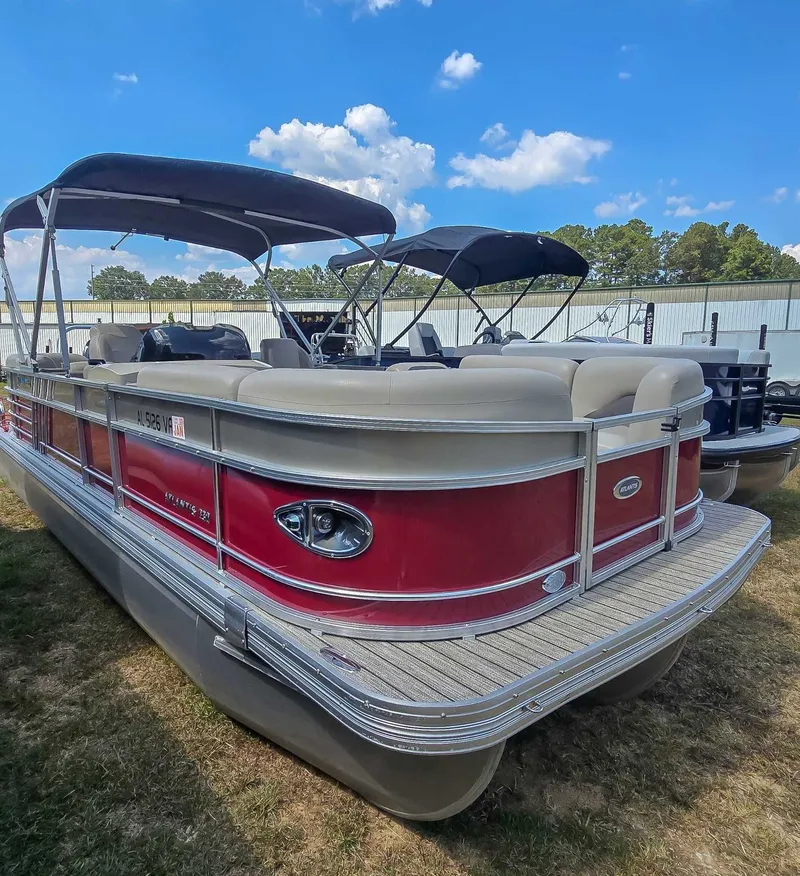Slide: The Image of 2020 Landau ATLANTIS pontoon boat with red exterior and canopy, parked outdoors. - 3