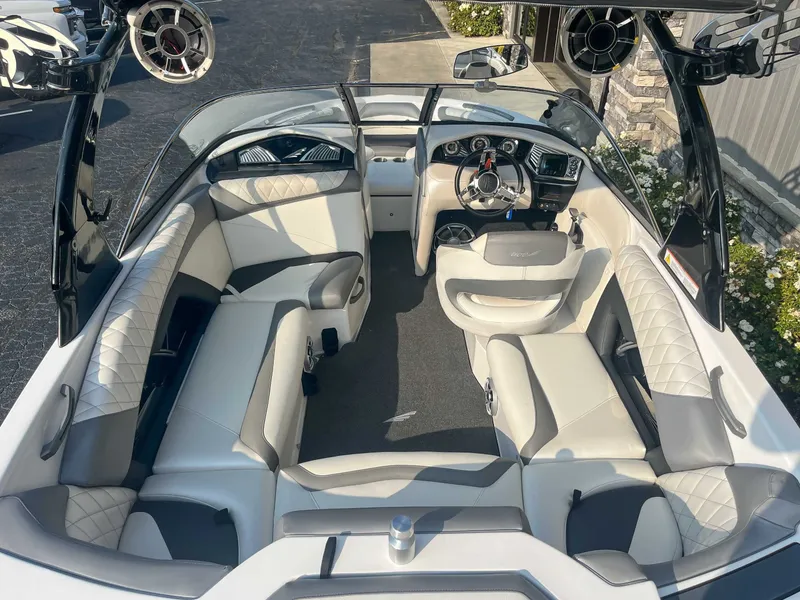 Slide: The Image of 2014 Tigé RZR boat interior with white and gray seating, steering wheel, and audio speakers. - 11