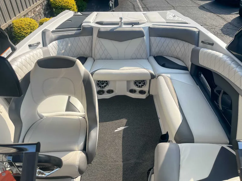 Slide: The Image of 2014 Tigé RZR boat interior with white and gray seating, featuring speakers and quilted upholstery. - 13