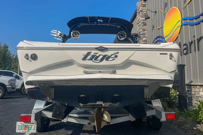 Slide: The Image of 2014 Tigé RZR boat on trailer, parked outside a marina building. - 7
