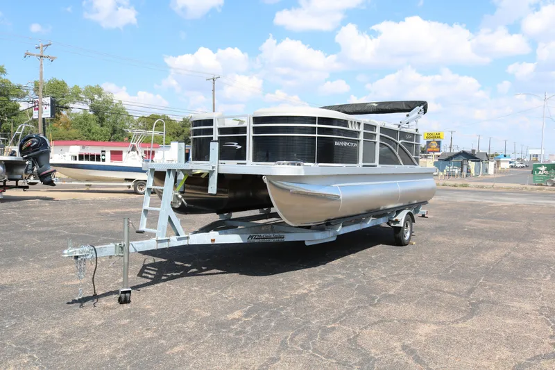 Slide: The Image of 2026 Bennington 20SSRCX pontoon boat on trailer, parked outdoors under a blue sky. - 3