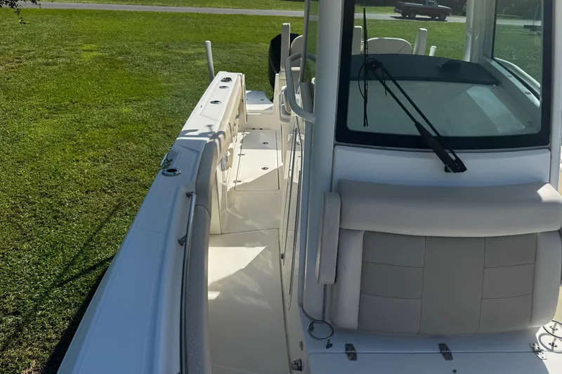 Slide: The Image of 2019 Boston Whaler 26 Outrage boat, white interior, parked on grass. - 11