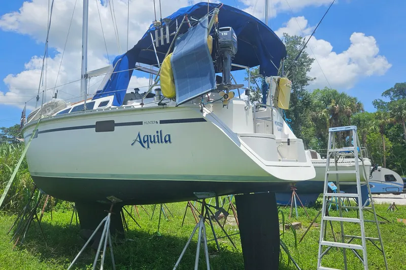 Slide: The Image of 1991 Hunter 34 sailboat "Aquila" on stands, with blue canopy and ladder nearby. - 20