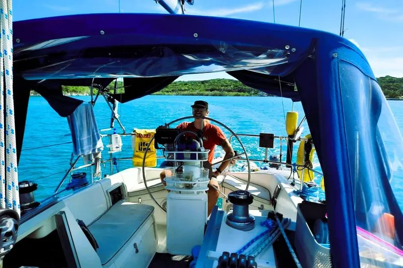 Slide: The Image of Person steering a 1992 Hunter 33.5 sailboat on clear blue water. - 3