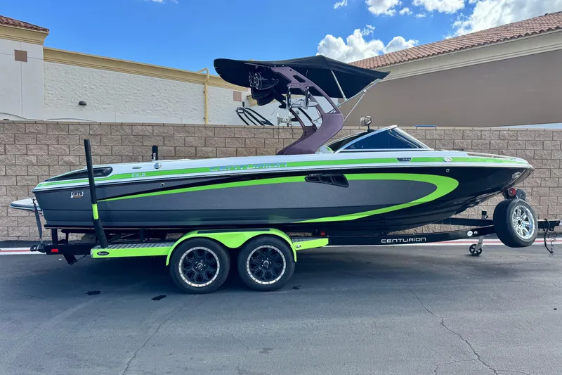 The Image of 2014 Centurion Enzo SV244 boat with green accents on a trailer, parked outdoors. - 1