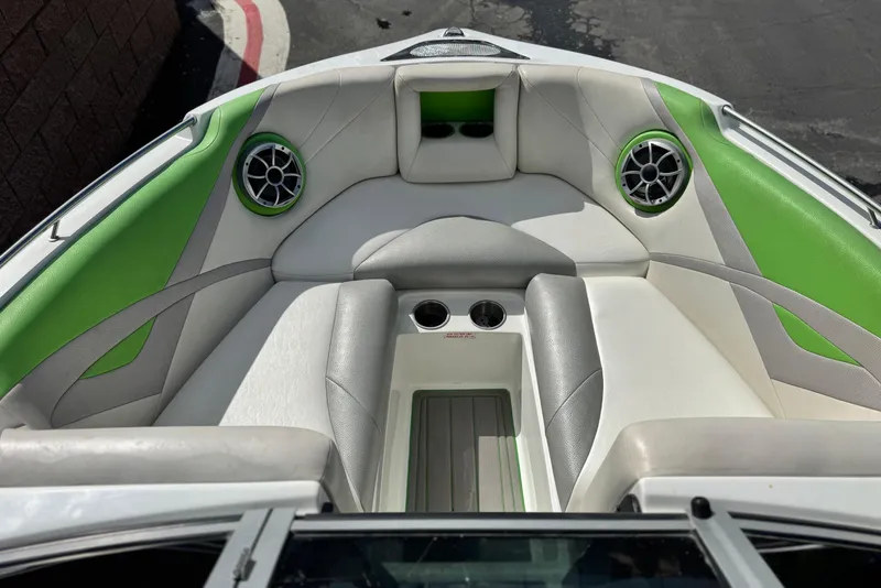 Slide: The Image of 2014 Centurion Enzo SV244 boat interior with green and gray seating, cup holders, and speakers. - 13