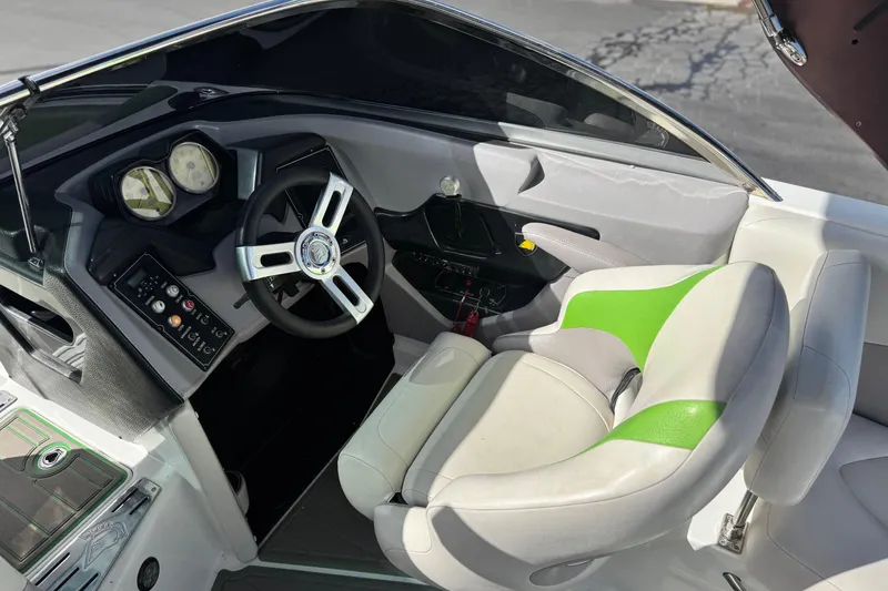 Slide: The Image of 2014 Centurion Enzo SV244 boat cockpit with steering wheel and green-accented seat. - 15