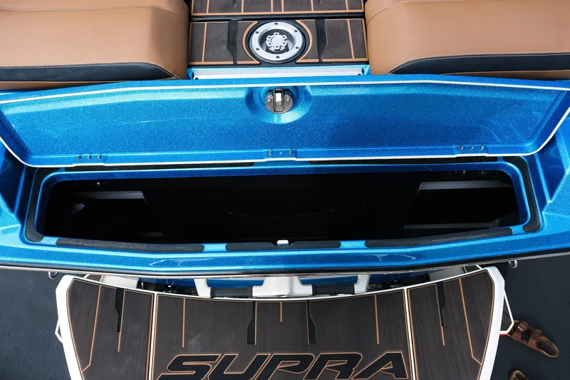 Slide: The Image of 2023 Supra SE550 boat storage compartment with blue finish and brown seating. - 10