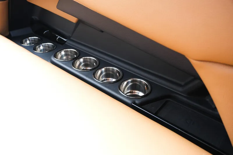 Slide: The Image of 2023 Supra SE550 interior cup holders with sleek design and tan leather accents. - 15