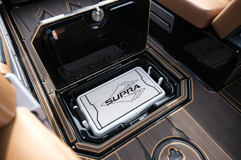 Slide: The Image of 2023 Supra SE550 boat interior with storage compartment and branded cooler. - 24