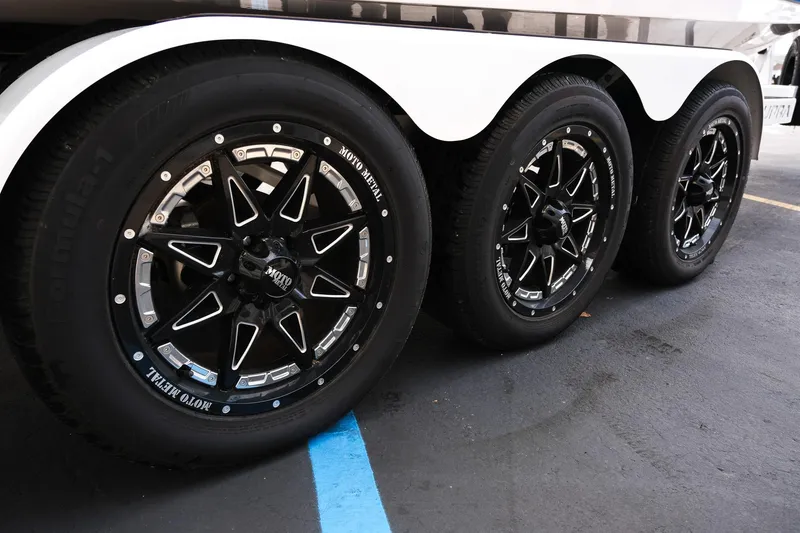 Slide: The Image of 2023 Supra SE550 trailer wheels with black Moto Metal rims on pavement. - 33