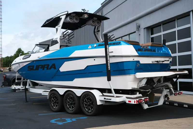 Slide: The Image of 2023 Supra SE550 boat in blue and white on a trailer outside a building. - 4