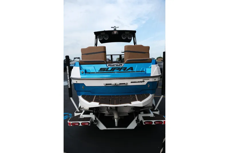 Slide: The Image of 2023 Supra SE550 boat, rear view, blue and white design, on trailer. - 7