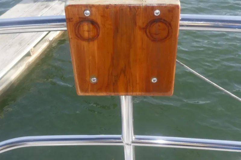 Slide: The Image of Polished wooden panel on Tartan 37 sailboat, 1989, with metal railings and water backdrop. - 14