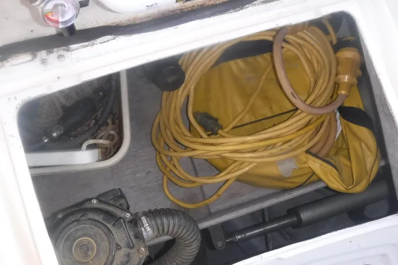 Slide: The Image of Storage compartment of 1989 Tartan 37 sailboat with yellow hose and equipment. - 16