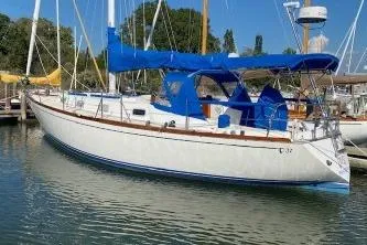 Slide: The Image of 1989 Tartan 37 sailboat docked, featuring blue sail covers and a sleek white hull. - 2