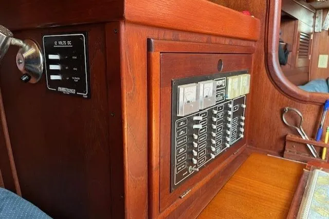 Slide: The Image of Control panel inside a 1989 Tartan 37 sailboat, featuring wooden cabinetry and electrical switches. - 35