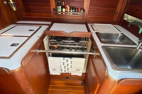 Slide: The Image of 1989 Tartan 37 yacht kitchen with stove, sink, and wooden cabinetry. - 37