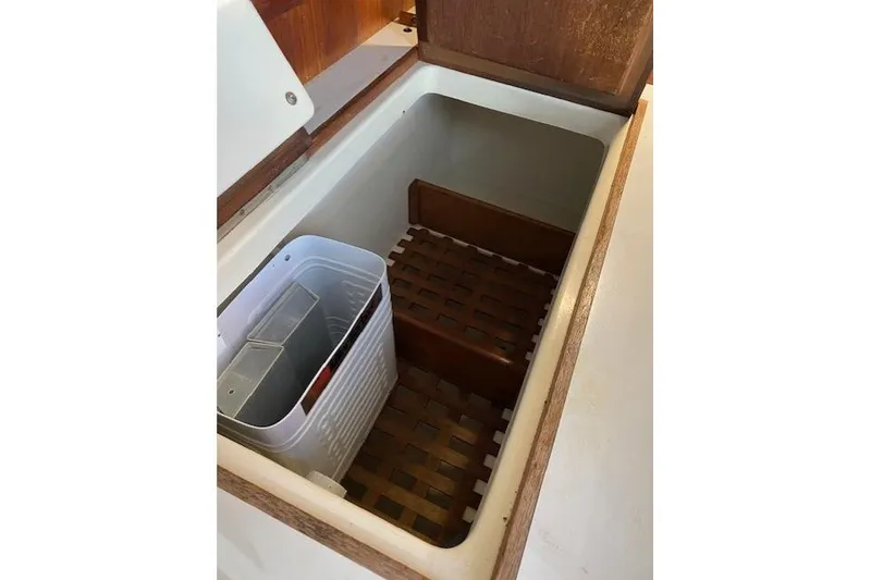 Slide: The Image of Open storage compartment in 1989 Tartan 37 sailboat with wooden lattice and plastic container. - 41
