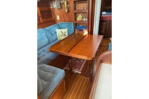 Slide: The Image of 1989 Tartan 37 yacht interior with wooden table, blue cushioned seating, and nautical decor. - 47