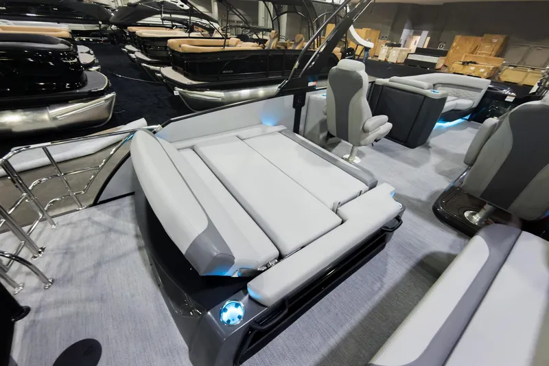 Slide: The Image of 2026 Godfrey Monaco 25' Tritoon with luxurious flip lounge seating, showcased indoors. - 26