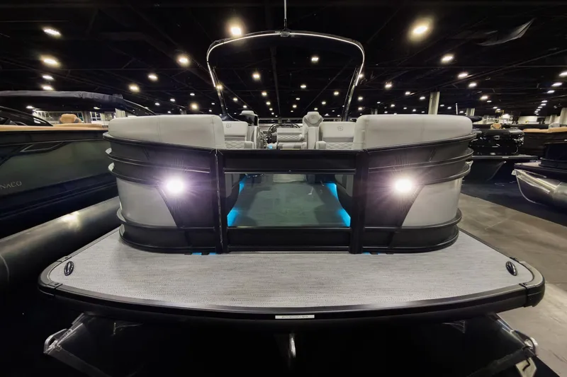 Slide: The Image of 2026 Godfrey Monaco 25' Tritoon with illuminated deck and sleek design in showroom. - 5