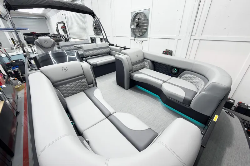 Slide: The Image of 2026 Godfrey Monaco 25' Tritoon with luxurious gray seating and modern interior design. - 11