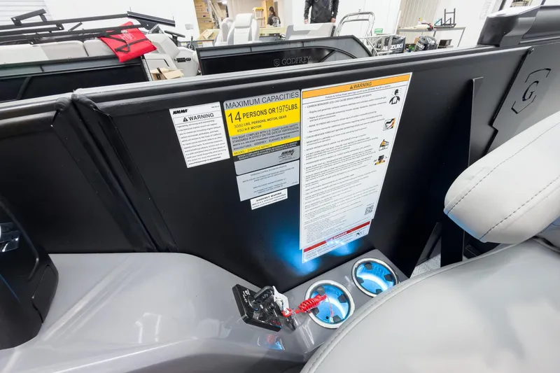 Slide: The Image of Interior view of 2026 Godfrey Monaco 25' Tritoon, showing capacity warning and cup holders. - 26