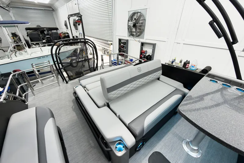 Slide: The Image of Luxurious 2026 Godfrey Monaco 25' Tritoon with mid-table flip lounge in a sleek indoor setting. - 41