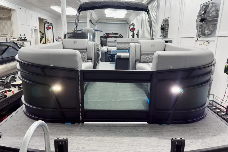 Slide: The Image of 2026 Godfrey Monaco 25' Tritoon with luxurious seating in a showroom setting. - 5