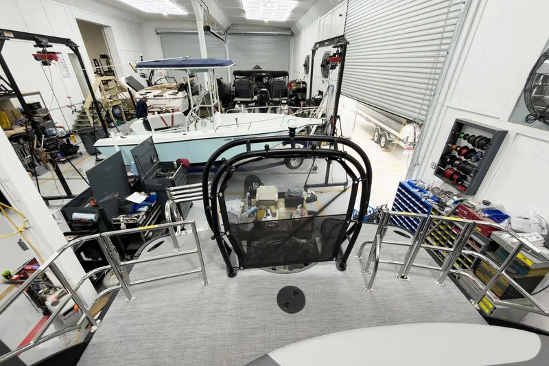 Slide: The Image of 2026 Godfrey Monaco 25' Tritoon in a workshop, surrounded by tools and equipment. - 52