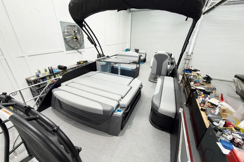 Slide: The Image of 2026 Godfrey Monaco 25' Tritoon with mid-table flip lounge in a workshop setting. - 54