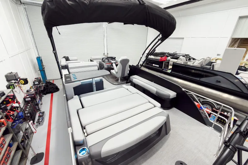 Slide: The Image of 2026 Godfrey Monaco 25' Tritoon with mid-table flip lounge in a showroom. - 56