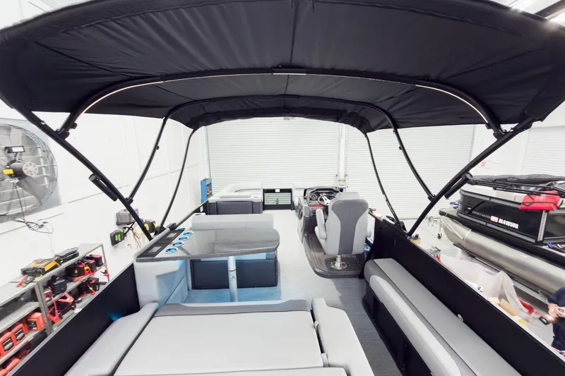 Slide: The Image of 2026 Godfrey Monaco 25' Tritoon with mid-table flip lounge and canopy in showroom. - 62