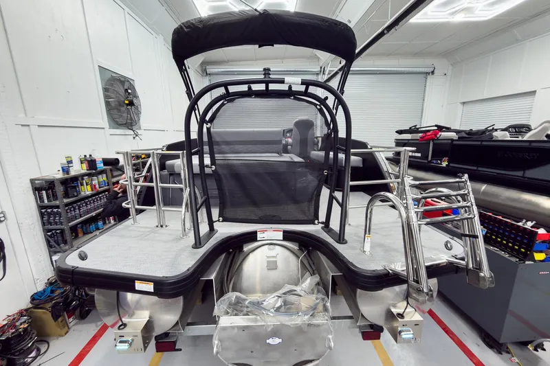 Slide: The Image of 2026 Godfrey Monaco 25' Tritoon in workshop, showcasing rear deck and seating. - 8