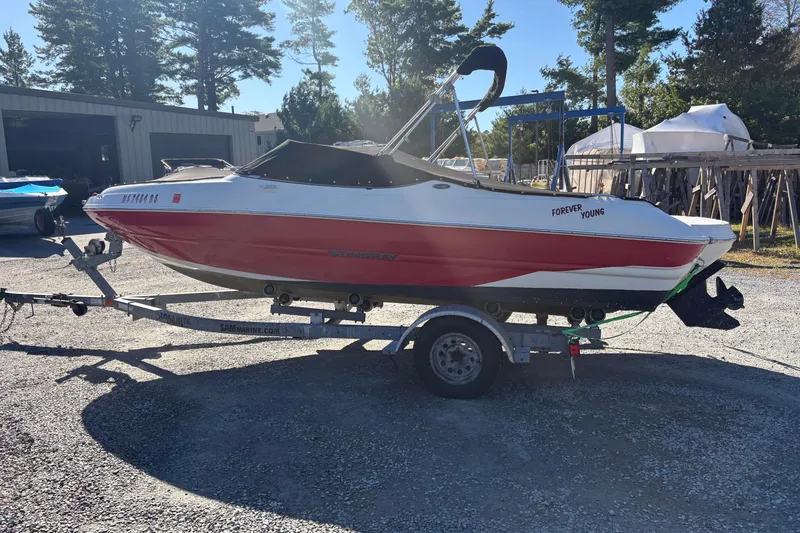 The Image of 2014 Stingray 198 LX boat on trailer, red and white, parked outdoors. - 0