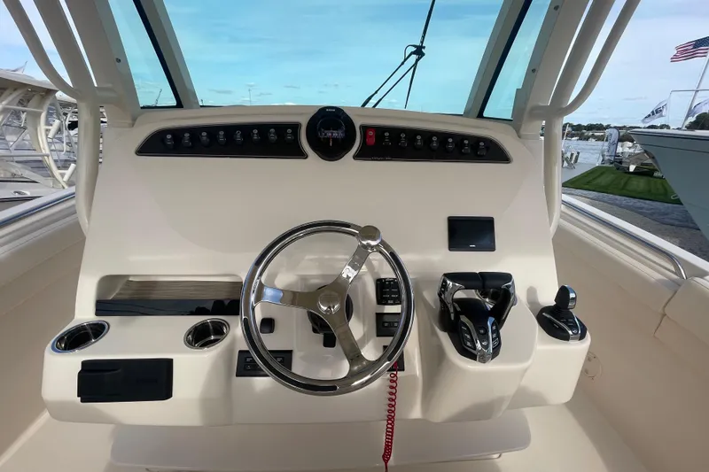 Slide: The Image of 2026 Grady-White Canyon 326 helm with steering wheel and controls, docked by the water. - 12