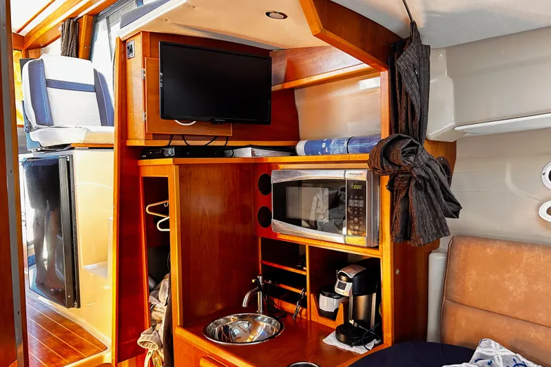 Slide: The Image of 2014 Cutwater C-28 interior with TV, microwave, and coffee maker in wooden cabinetry. - 21