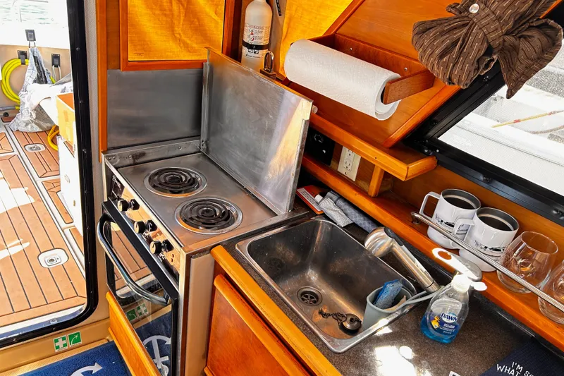 Slide: The Image of 2014 Cutwater C-28 boat kitchen with stove, sink, and wooden cabinetry. - 22