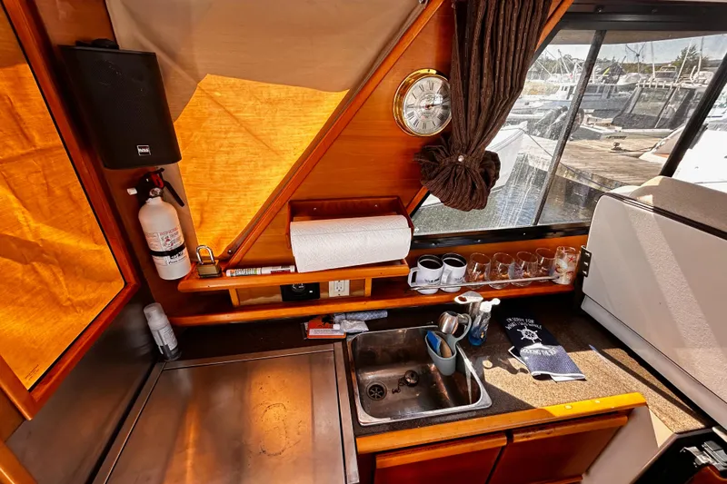 Slide: The Image of 2014 Cutwater C-28 boat interior with kitchen sink, clock, and window view of marina. - 23