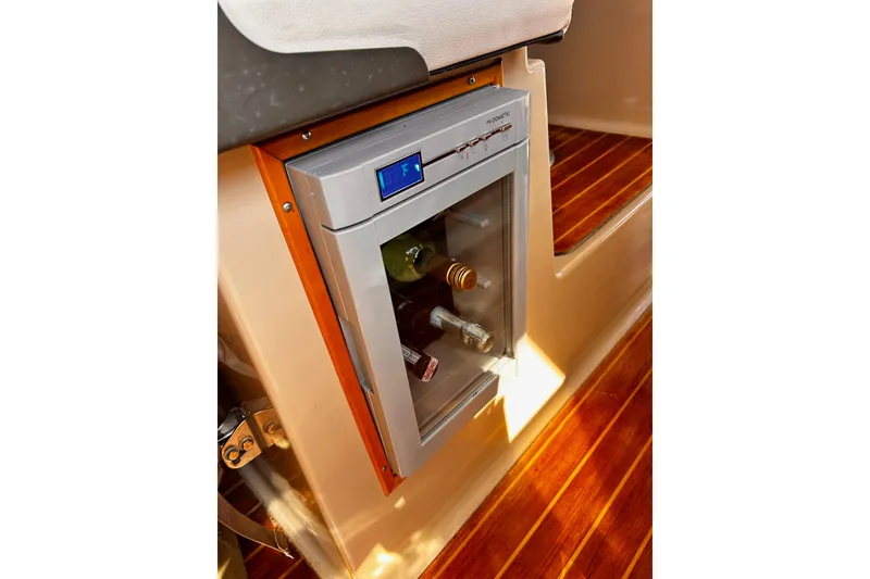 Slide: The Image of 2014 Cutwater C-28 interior with a compact fridge, wooden flooring, and beverage storage. - 26