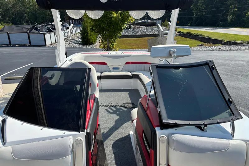 Slide: The Image of 2016 Malibu Wakesetter 24 MXZ interior with red and white seating, open windshield, and outdoor setting. - 5