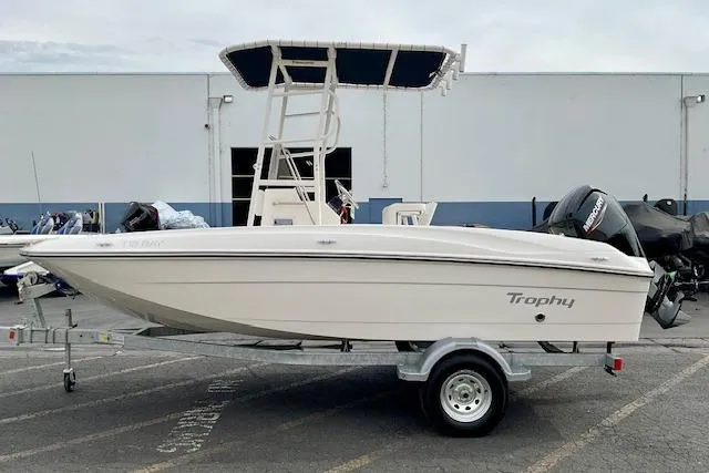 Slide: The Image of 2025 Bayliner Trophy T18 boat on trailer, parked outdoors near a building. - 1