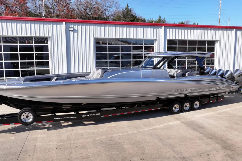 Slide: The Image of 2024 MTI 50v boat on trailer, parked outside a garage. - 60