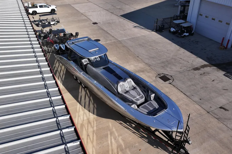 Slide: The Image of 2024 MTI 50v boat on trailer in industrial area, surrounded by vehicles and equipment. - 61