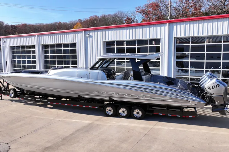 Slide: The Image of 2024 MTI 50v boat on trailer, parked outside a garage with glass doors. - 70
