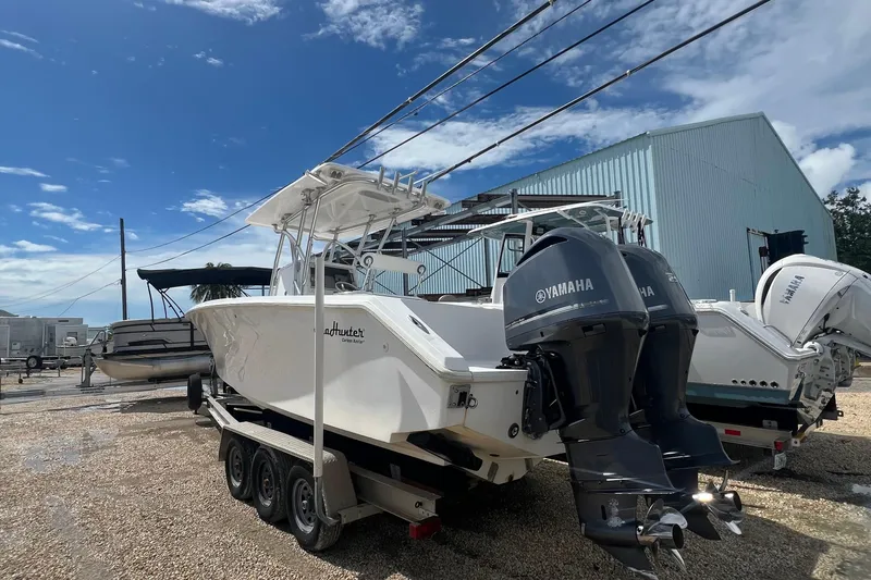 Slide: The Image of 2012 SeaHunter 29 boat with twin Yamaha engines on a trailer, parked outdoors. - 2